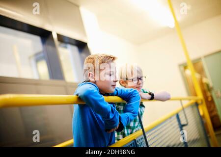 Les garçons s'inclinent à pleuvoir dans le bâtiment de l'école Banque D'Images