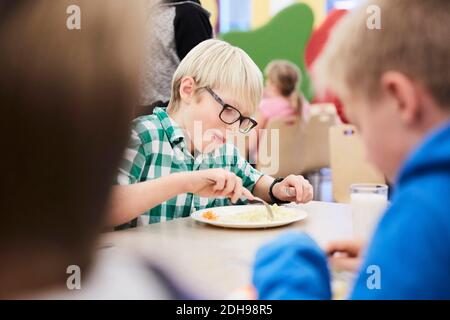 Garçon déjeunant à table dans la cafétéria de l'école Banque D'Images