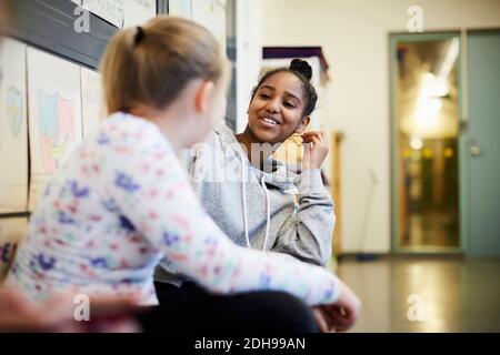 Fille d'école moyenne discutant avec une amie dans le couloir Banque D'Images