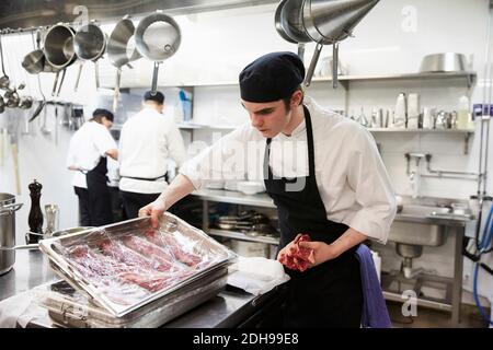 Plateau d'examen de viande de chef masculin enveloppé de plastique cuisine commerciale Banque D'Images