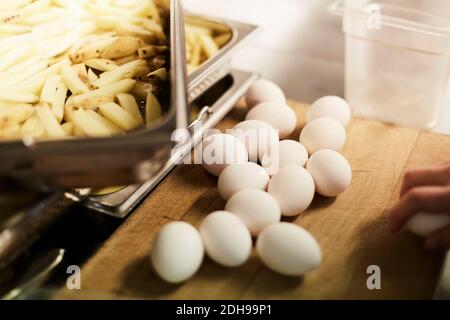 Vue en grand angle des œufs et des tranches de pommes de terre sur le comptoir dans la cuisine commerciale Banque D'Images