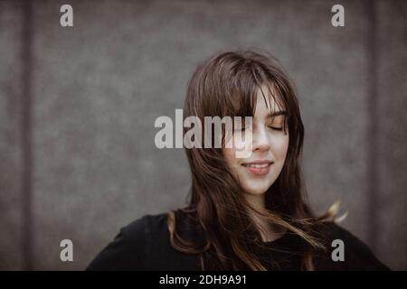 Femme souriante avec les yeux fermés debout à l'extérieur Banque D'Images