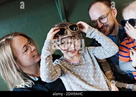 Bonne famille regardant la fille portant différentes lunettes sur le visage à l'atelier Banque D'Images