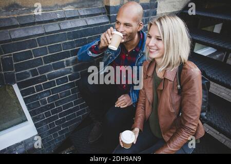 Couple prenant un café assis sur les marches Banque D'Images