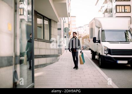 Liveur transportant des provisions tout en marchant sur le sentier de la ville Banque D'Images