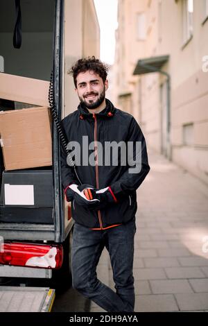 Portrait d'un jeune liveur confiant avec des boîtes dans un camion Banque D'Images
