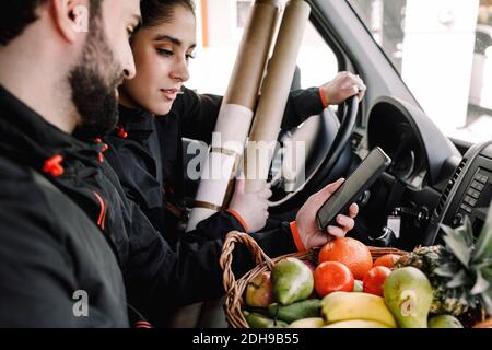 Liveur homme et femme avec des fruits et des paquets dans le camion Banque D'Images