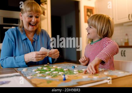 Grand-mère et petit-fils joyeux jouant à un jeu de société à la maison Banque D'Images