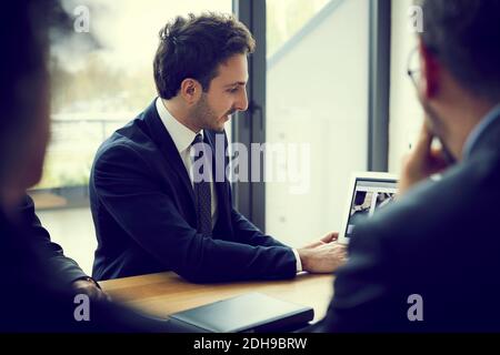 Un jeune conseiller financier explique la stratégie avec un ordinateur portable pendant la réunion dans un cabinet d'avocats Banque D'Images