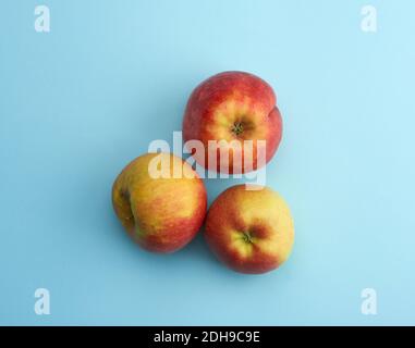 Les pommes rondes mûres rouges reposent sur un fond bleu Banque D'Images