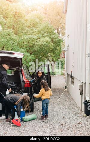 Famille chargeant des bagages dans une voiture électrique tout en allant pique-niquer Banque D'Images