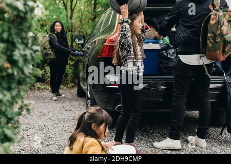 Fille avec parents chargeant des bagages dans le coffre électrique Banque D'Images