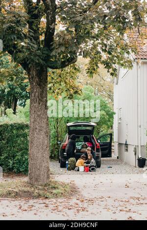 Famille chargeant des bagages dans le coffre d'une voiture électrique pendant son voyage pour pique-nique Banque D'Images