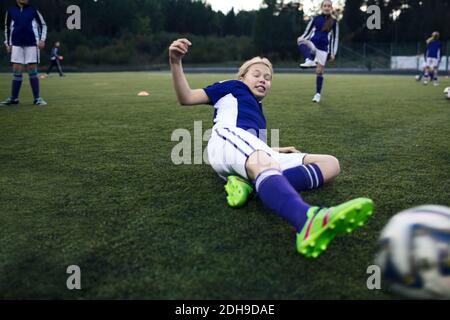 Une fille glisse sur l'herbe sur le terrain de football pendant l'entraînement Banque D'Images