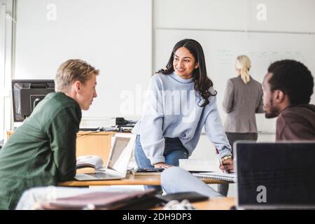 Jeune femme souriante parlant avec un étudiant en classe Banque D'Images
