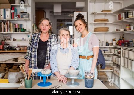 Portrait de potiers féminins souriants par établi dans un magasin de céramique Banque D'Images