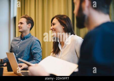 Bonne femme d'affaires assise avec des collègues masculins dans la salle de réunion du conseil Banque D'Images