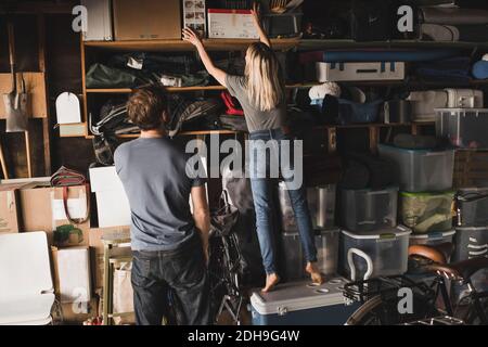 Vue arrière d'un homme regardant une femme qui organise des boîtes étagère dans la salle de stockage Banque D'Images
