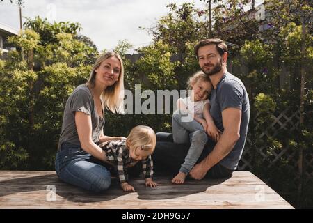 Portrait des parents et des enfants assis sur le plancher dans la cour Banque D'Images