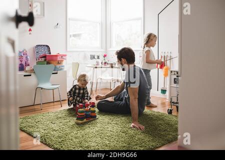 Père et filles jouant avec des jouets dans la salle de jeux à la maison Banque D'Images