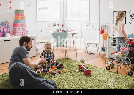 Père et filles jouant avec des jouets dans la salle de jeux à la maison Banque D'Images