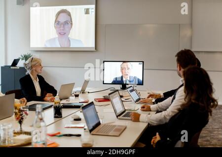Professionnels de sexe masculin et féminin ayant une réunion de vidéoconférence à bord chambre au bureau Banque D'Images