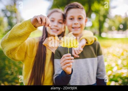 Amitié entre frères et sœurs. Des frères et sœurs à l'extérieur avec un arrière-plan de couleur vive. Portrait d'automne des enfants. Frère et sœur Banque D'Images