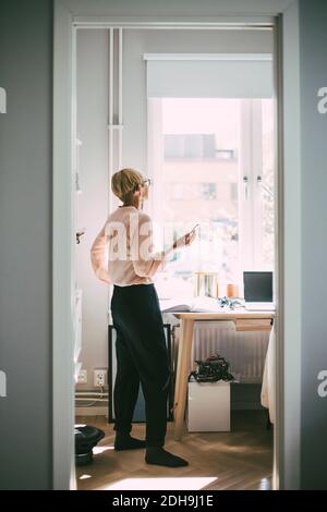 Femme au bureau à domicile parlant au téléphone Banque D'Images