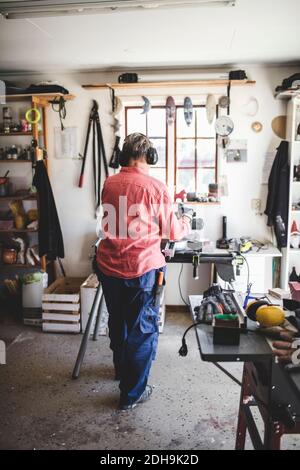Vue arrière complète de la femme âgée travaillant dans l'atelier Banque D'Images