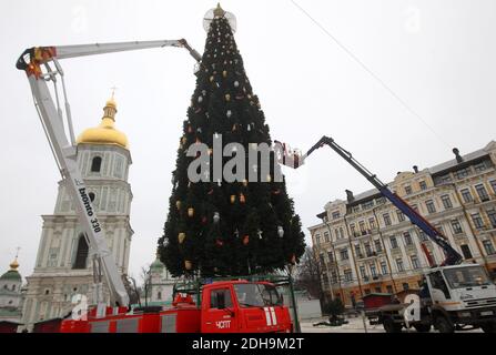 Un ouvrier municipal décorera le principal arbre de Noël de l'Ukraine devant la cathédrale Sainte-Sophie à Kiev en préparation des fêtes de Noël et du nouvel an. Banque D'Images