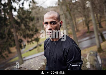 Portrait d'un athlète masculin confiant debout en forêt Banque D'Images