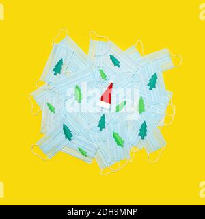 Masques médicaux de protection contre le coronavirus, décorés de papier arbre de Noël et d'un chapeau de Père Noël. Flat lay, espace de copie. Concept de coronavirus Banque D'Images