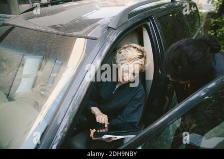 Femme mécanicien discutant avec le client au sujet d'une tablette numérique en voiture Banque D'Images