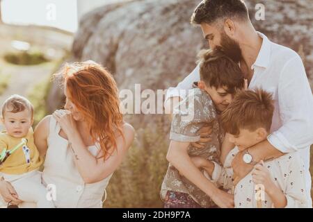 Père souriant embrassant des fils tandis que la mère regarde la petite fille contre la formation de roches Banque D'Images