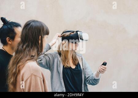 Programmateur utilisant la télécommande tout en portant des lunettes VR collègues au bureau Banque D'Images
