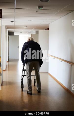 Vue arrière sur toute la longueur de l'homme qui marche avec un roller dans le couloir de l'hôpital Banque D'Images