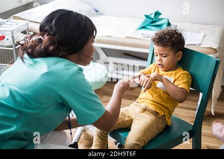 Pédiatre féminin pointant vers le bras du garçon à l'hôpital Banque D'Images