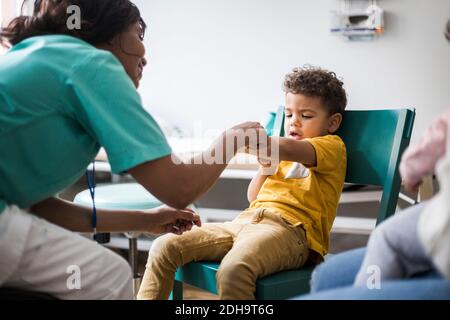 Femme médecin pointant vers le bras du garçon à l'hôpital Banque D'Images