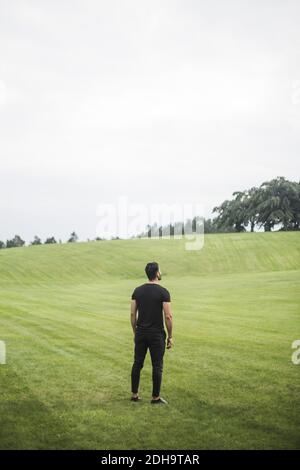 Vue arrière du jeune homme debout sur le terrain agricole contre ciel Banque D'Images