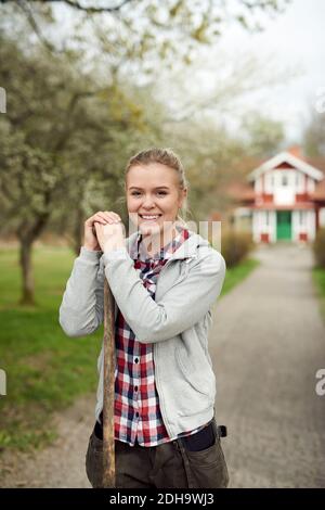 Portrait d'une adolescente souriante tenant une fourche tout en étant debout chemin de pied Banque D'Images