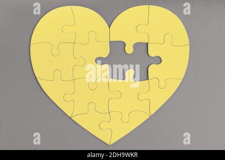 Couleur tendance de l'année 2021. Gris ultime et jaune lumineux. Pièce manquante de puzzle en forme de coeur. Amour, charité, concept de don Banque D'Images