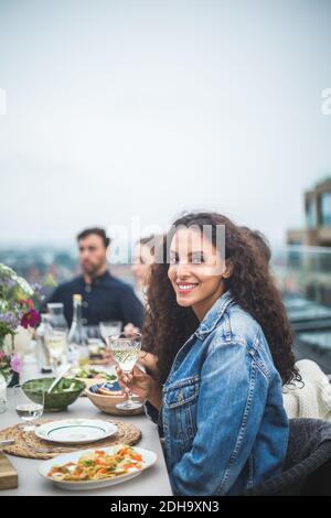 Portrait d'une femme souriante assise avec des amis lors d'un rassemblement social sur le toit Banque D'Images