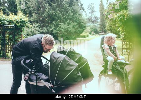 Le père pageing dans la poussette de bébé sur le sentier pendant la journée ensoleillée Banque D'Images