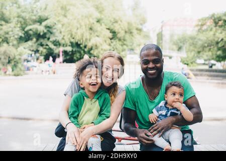Portrait de parents heureux avec des enfants assis au parc Banque D'Images
