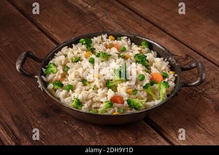 Riz végétal au brocoli, carottes et pois verts, dans une poêle sur fond de bois rustique Banque D'Images