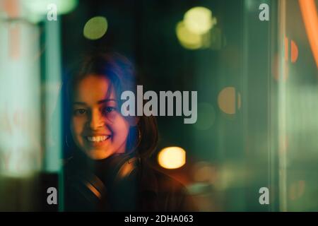Portrait d'une femme souriante avec un casque dans la ville la nuit Banque D'Images