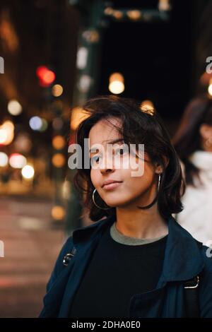 Femme contemplant debout dans la ville illuminée la nuit Banque D'Images