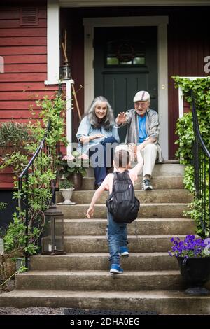 Vue arrière d'un garçon agitant les grands-parents assis sur le devant stop Banque D'Images