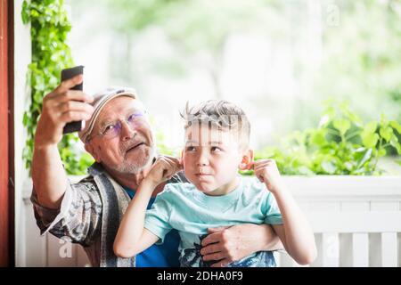 Grand-père prenant le selfie avec petit-fils dans le porche Banque D'Images