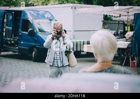Touriste senior prenant la photo d'une femme en se tenant en ville Banque D'Images